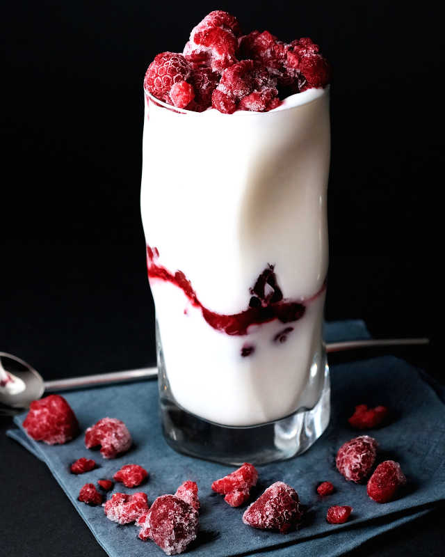 tall glass fruit parfait with raspberries on the top